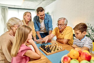 Portrait of a three generation family, grandparents, parents and children playing chess and having fun at home