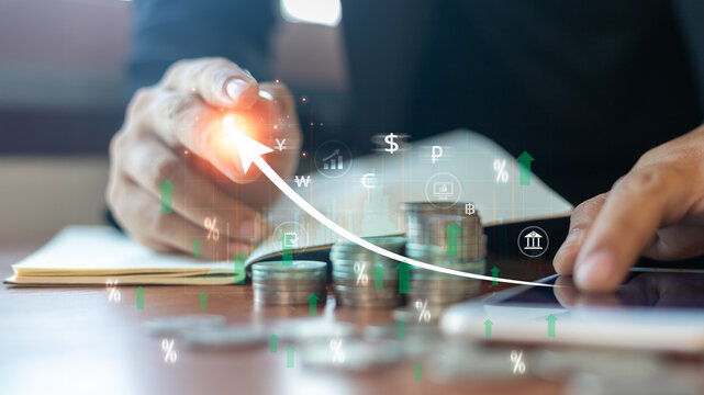 A businessman hand touches a virtual graph with currency symbols and a rising arrow over stacked coins - Powered by Adobe