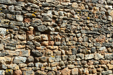 Stone wall displaying rustic texture and varied colors in a natural setting during daylight