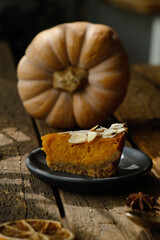 Slice of pumpkin pie sprinkled with sliced almonds. Homemade traditional American thanksgiving pie