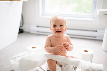 Toddler ripping up toilet paper in bathroom