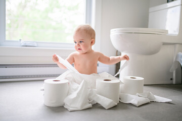 Toddler ripping up toilet paper in bathroom