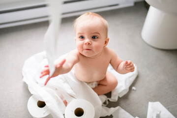 Toddler ripping up toilet paper in bathroom