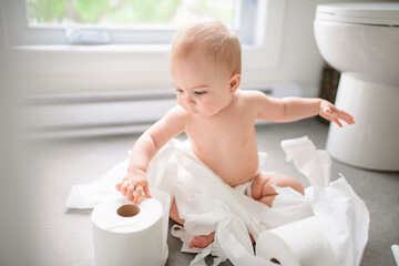 Toddler ripping up toilet paper in bathroom