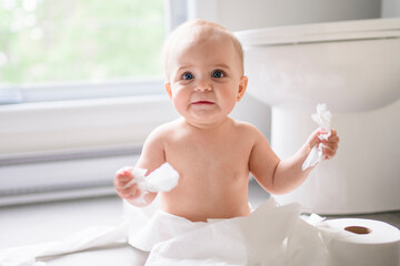 Toddler ripping up toilet paper in bathroom