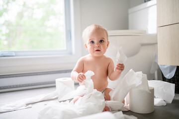 Toddler ripping up toilet paper in bathroom