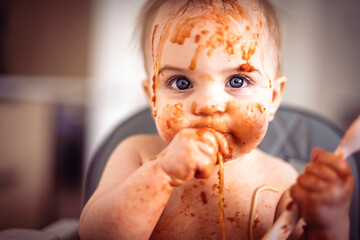 Little baby eating her dinner and making a mess