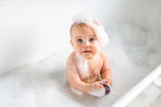 Cute little child bathing in tub at home
