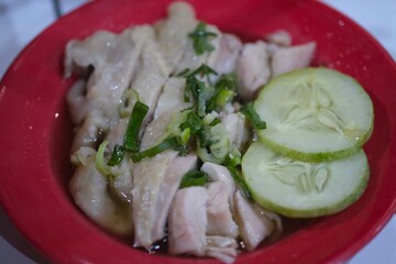 Close up of Hainanese chicken chop served with cucumber and leek on red plate