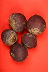 This top-down shot showcases five whole, unpeeled beetroots with their earthy textures, arranged on a vibrant red background