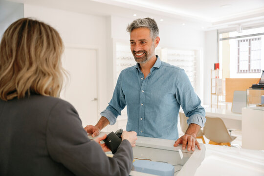 Optician assisting a client at the counter in a bright store