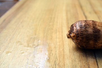 Fresh Unpeeled Taro Root Vegetable On Wooden Table Close Up With Background Blur