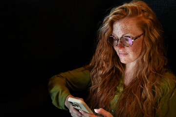 Red-haired woman using smartphone in an office setting