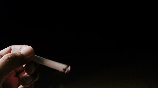 Close up man hand smoking cigarette on black background