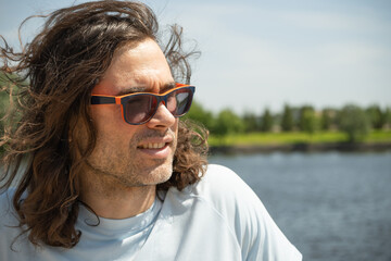Happy caucasian brunette man in sunglasses wearing casual blue t-shirt sunglasses stand at urban...