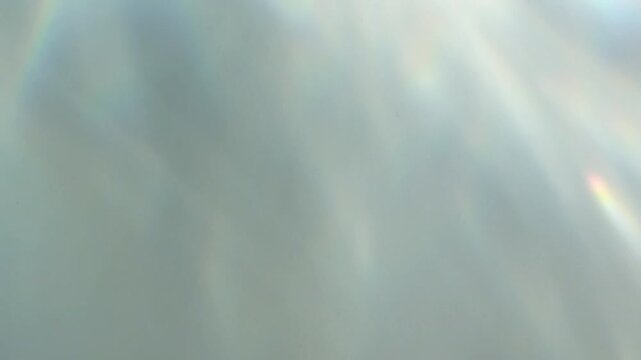 Soft abstract light reflections with iridescent highlights. Gentle pastel gradients and dreamy motion suggest a holographic or surreal atmosphere.