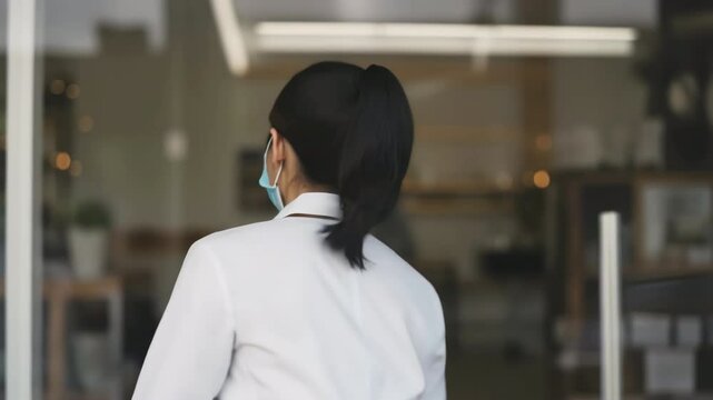 Business Reopening Announcement by a Woman with Mask Holding Open Sign in a Shop's Window Urban Setting Indoor Scene Close-up View for Safety and Community Engagement