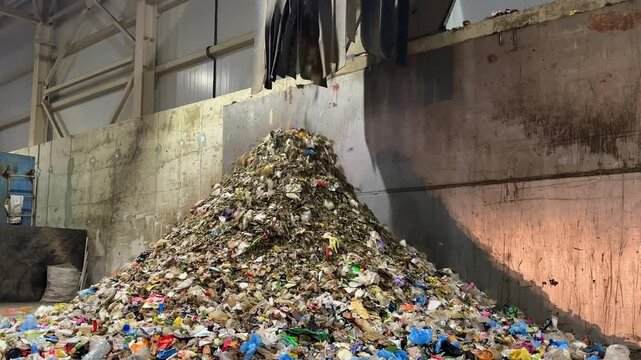 Conveyor belt waste drum filter rotating cylindrical screen drum sorts pieces into fractions of different sizes in recycling plant. Falling trash mountain heap, landfill of screened waste for compost