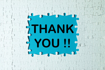 A white jigsaw puzzle with a missing piece revealing the words THANK YOU. A creative concept for...
