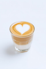 Glass of creamy latte with heart-shaped milk foam art on top, placed on light marble surface. Warmth, love, and coffee culture.