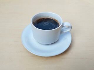 Black coffe in white glass on wooden table background 