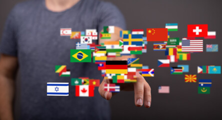 A man interacts with a digital display of world flags, symbolizing global connection and...
