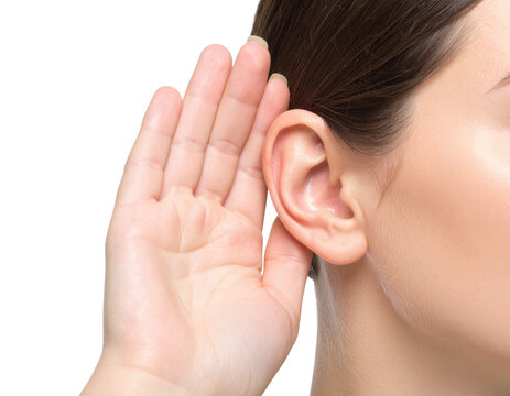 A close-up image of a woman holding her hand behind her ear, as if trying to listen carefully.
