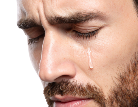 Close-up of a man with a beard shedding a tear, expressing deep emotion and vulnerability against a black background.