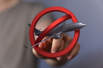 Image of a hand holding a no symbol over a model airplane.  Perfect for travel ban, restrictions,...