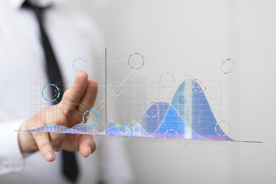 Stock photo of a businessman interacting with a holographic display showing financial data graphs and charts.
