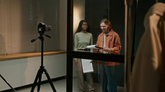 African American actress and Caucasian actor holding scripts and acting out scene together on camera on studio set
