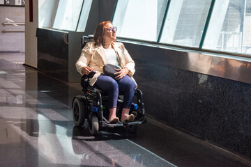 Businesswoman in wheelchair moving through subway station corridor. Concept of inclusion, adapted