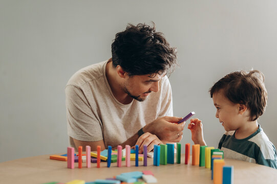 Father and son playing with colorful dominoes at home