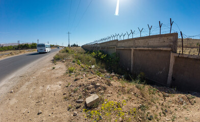 Roadside View with Barbed Wire Wall and Bus In Syria.