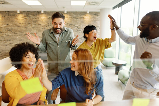 Enthusiastic team celebrating success with high fives in an office