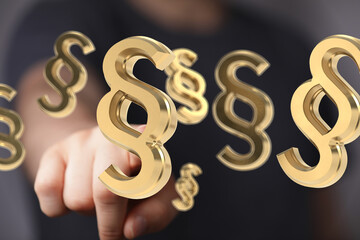Abstract image of golden paragraph symbols floating above a hand, representing legal concepts.