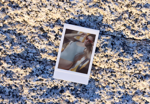 An empty instant photo template lies on a rough, textured surface