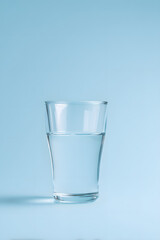 Minimalist photo of a transparent glass filled with clean drinking water, placed on a bright neutral background. Concept of hydration and healthy lifestyle.
