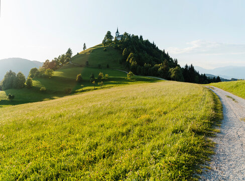 Scenic view of Saint Jacob Hill in Slovenia with lush green fields and mountains.