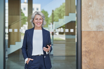 Businesswoman at trade fair holding smartphone outdoors