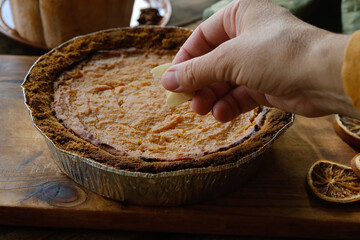 Sprinkle pumpkin pie with sliced almonds. Cooking homemade traditional Thanksgiving pie