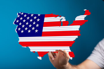 Patriotic image of the United States map designed like the American flag held in a person's hand.