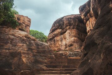 Ancient stone steps carved into reddish rock, leading through a narrow rocky canyon passage.