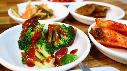 Fresh broccoli with savory brown sauce Korean side dish banchan served on white plate as part of traditional Korean meal