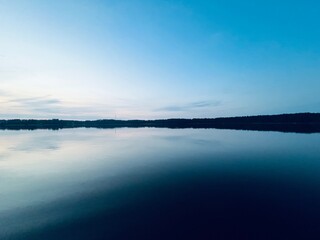 Peaceful evening lake reflection, sky and trees silhouettes on the lake surface, summer lake in the countryside