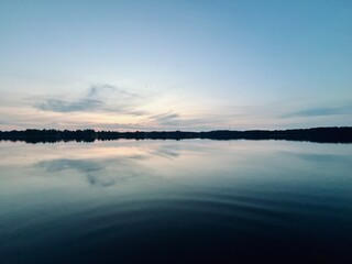 Peaceful evening lake reflection, sky and trees silhouettes on the lake surface, summer lake in the...