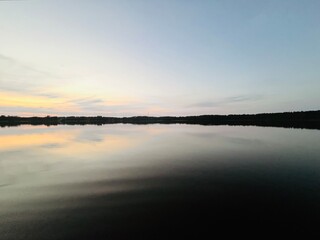 Peaceful evening lake reflection, sky and trees silhouettes on the lake surface, summer lake in the countryside