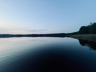 Peaceful evening lake reflection, sky and trees silhouettes on the lake surface, summer lake in the...