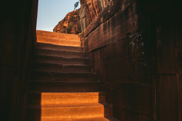 Old stone steps leading upward through an ancient structure in warm light.