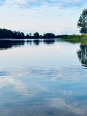 Peaceful evening lake reflection, sky and trees silhouettes on the lake surface, summer lake in the...